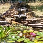 Une fontaine constituée de 3 Vasques Vives Dyana sur un bassin avec des nénuphars.